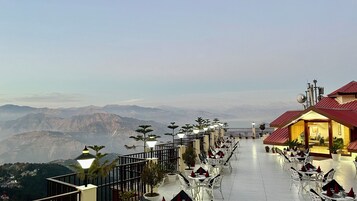 Un restaurante con terraza al aire libre y vistas a un paisaje montañoso.