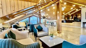 En moderne hotellobby med trælofter, behagelige siddepladser, en receptionsdisk og udsigt til det fri.