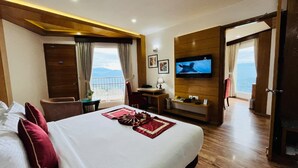 Hotelkamer met een groot bed, een bureau, een televisie en een balkon met uitzicht.