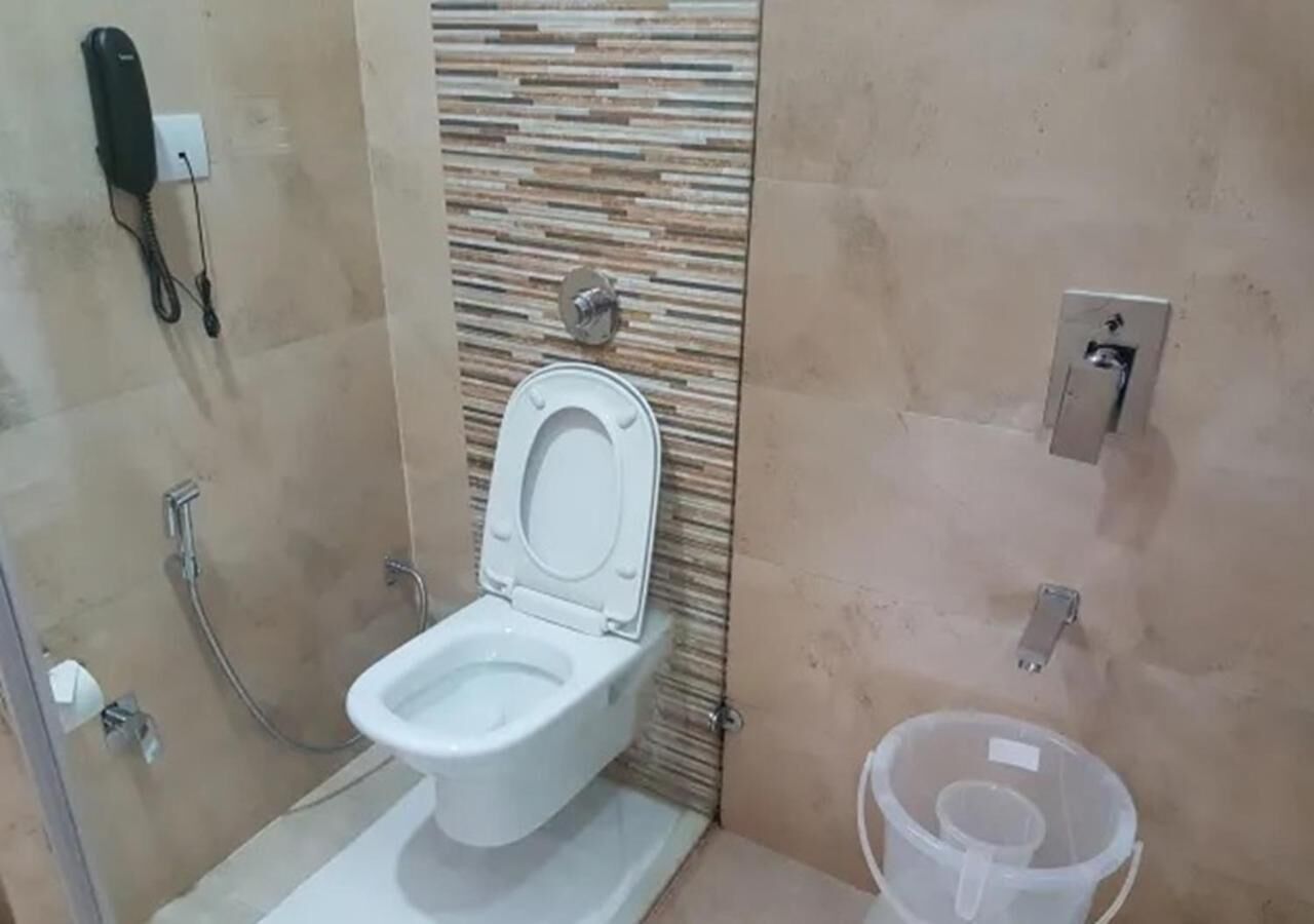 A bathroom with a toilet, a shower, and a hand dryer.