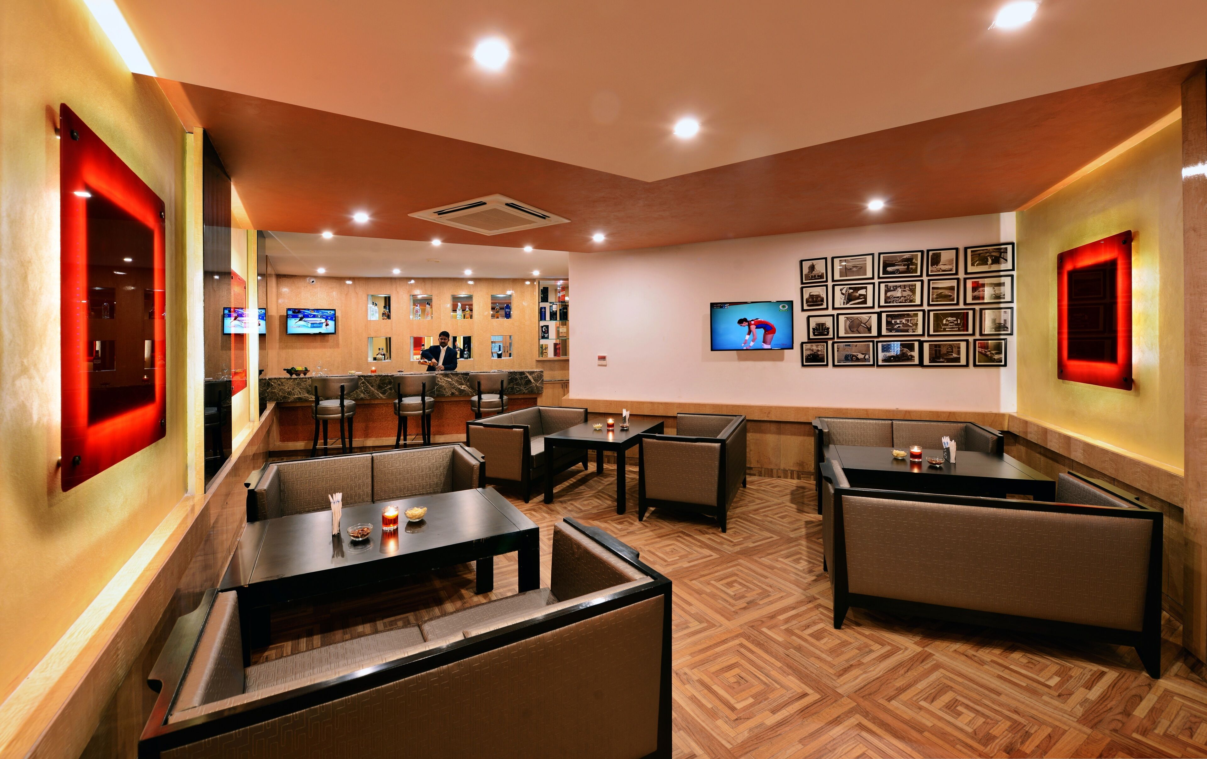 Un restaurante con cabinas y mesas, una zona de bar y una pared con cuadros enmarcados.