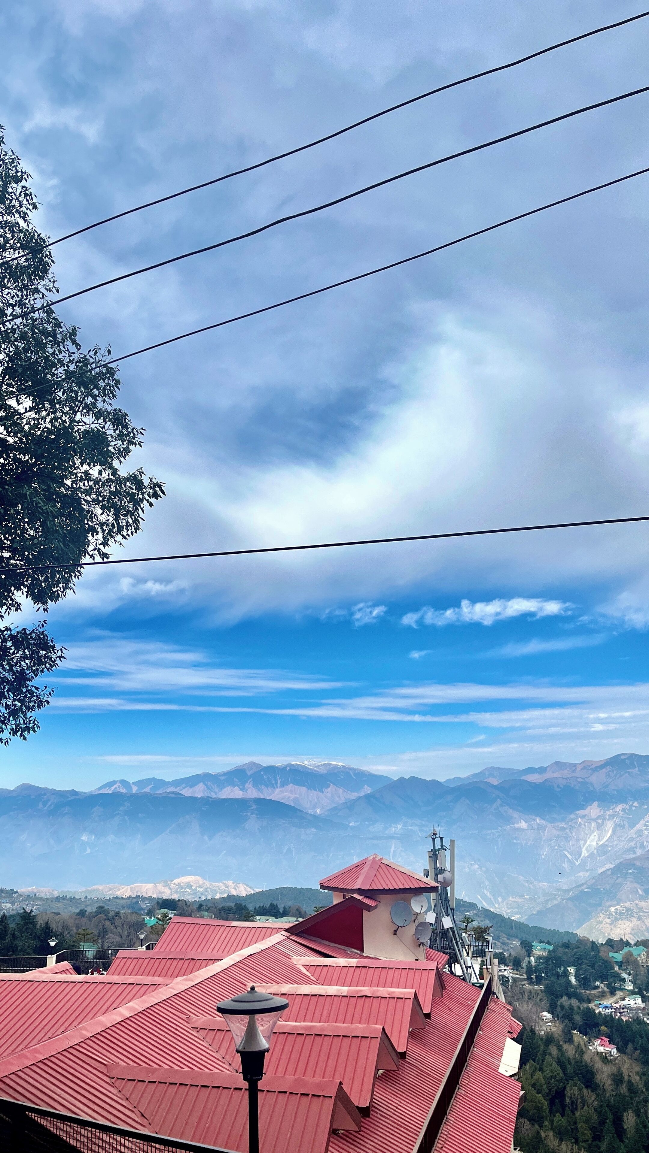 A building with red roofs, a mountainous landscape in the background, and power lines overhead.