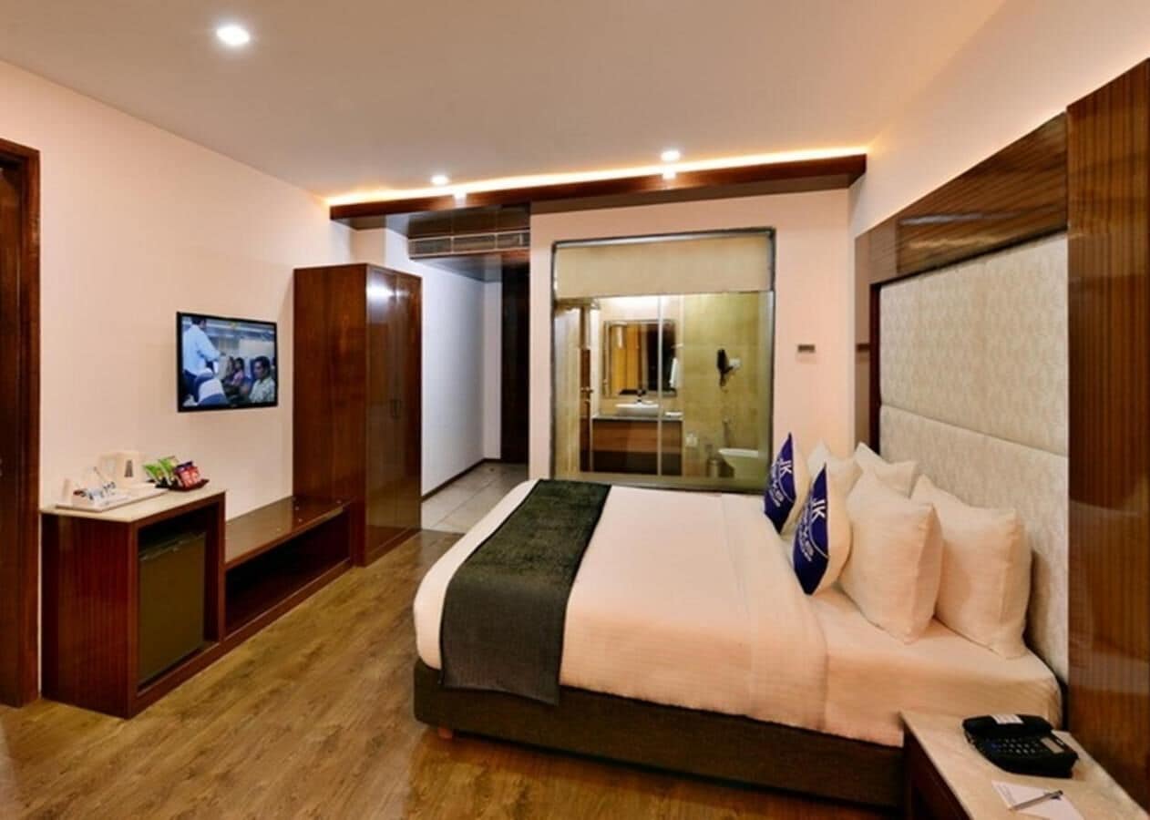 A modern hotel room with a large bed, a desk, and a television.