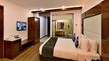 A modern hotel room with a large bed, a desk, and a television.