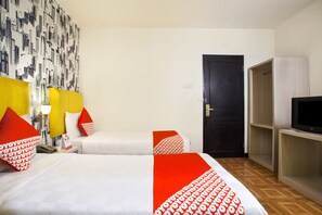 A hotel room with two beds, a TV, and a wardrobe. - Belvena Hotel (Jakarta)