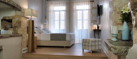 Quarto com uma cama, mesa de cabeceira, abajur, cadeira e parede de pedra.