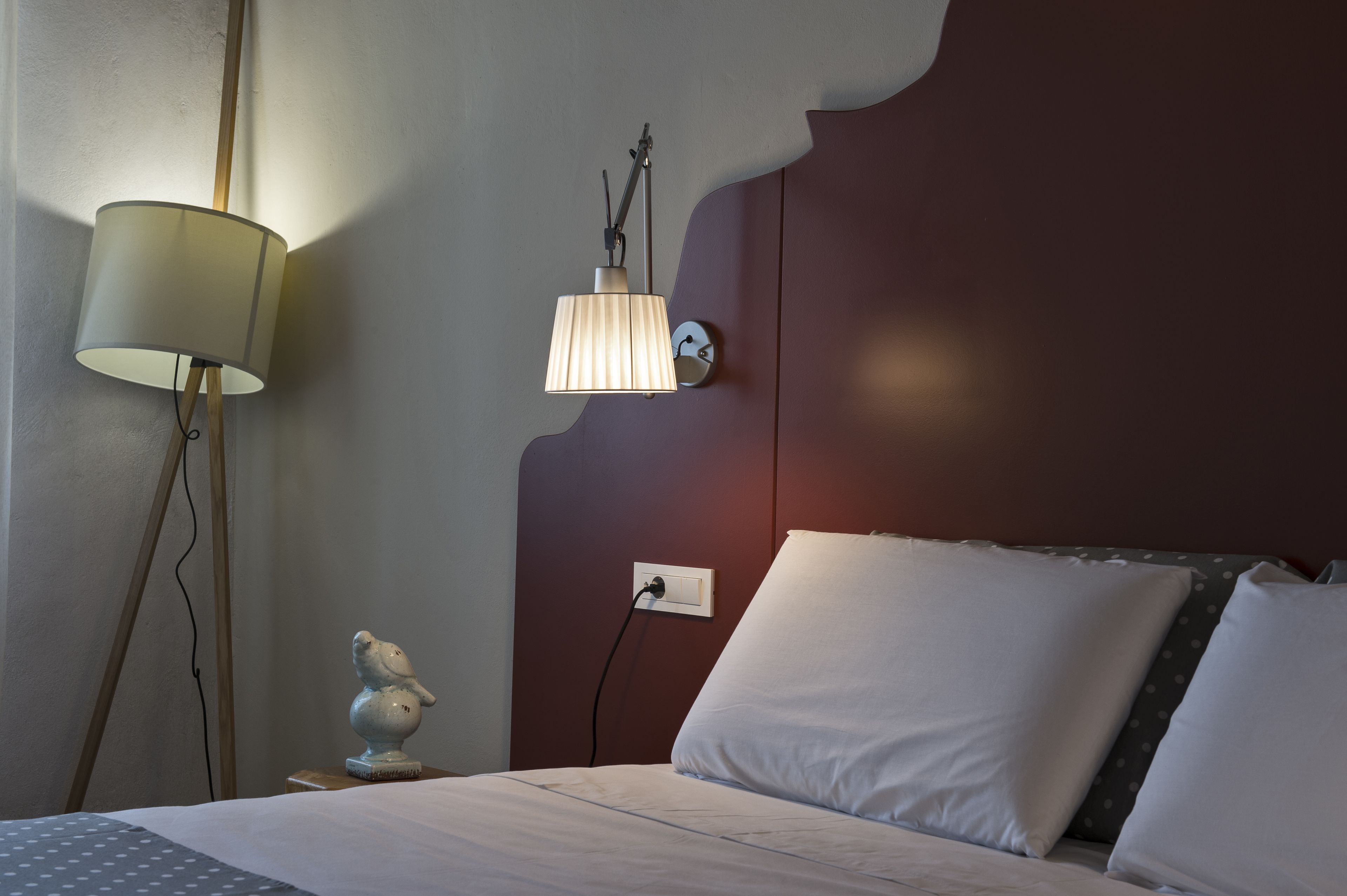 A neatly made bed with white linens, a bedside lamp, and a small decorative object on the nightstand.