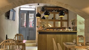Een gezellig eetgedeelte met houten meubels, een bar met flessen en een uitzicht door een rondboogdeur.