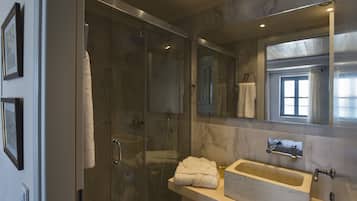 A modern bathroom with a glass-enclosed shower, a marble sink, and a large mirror.