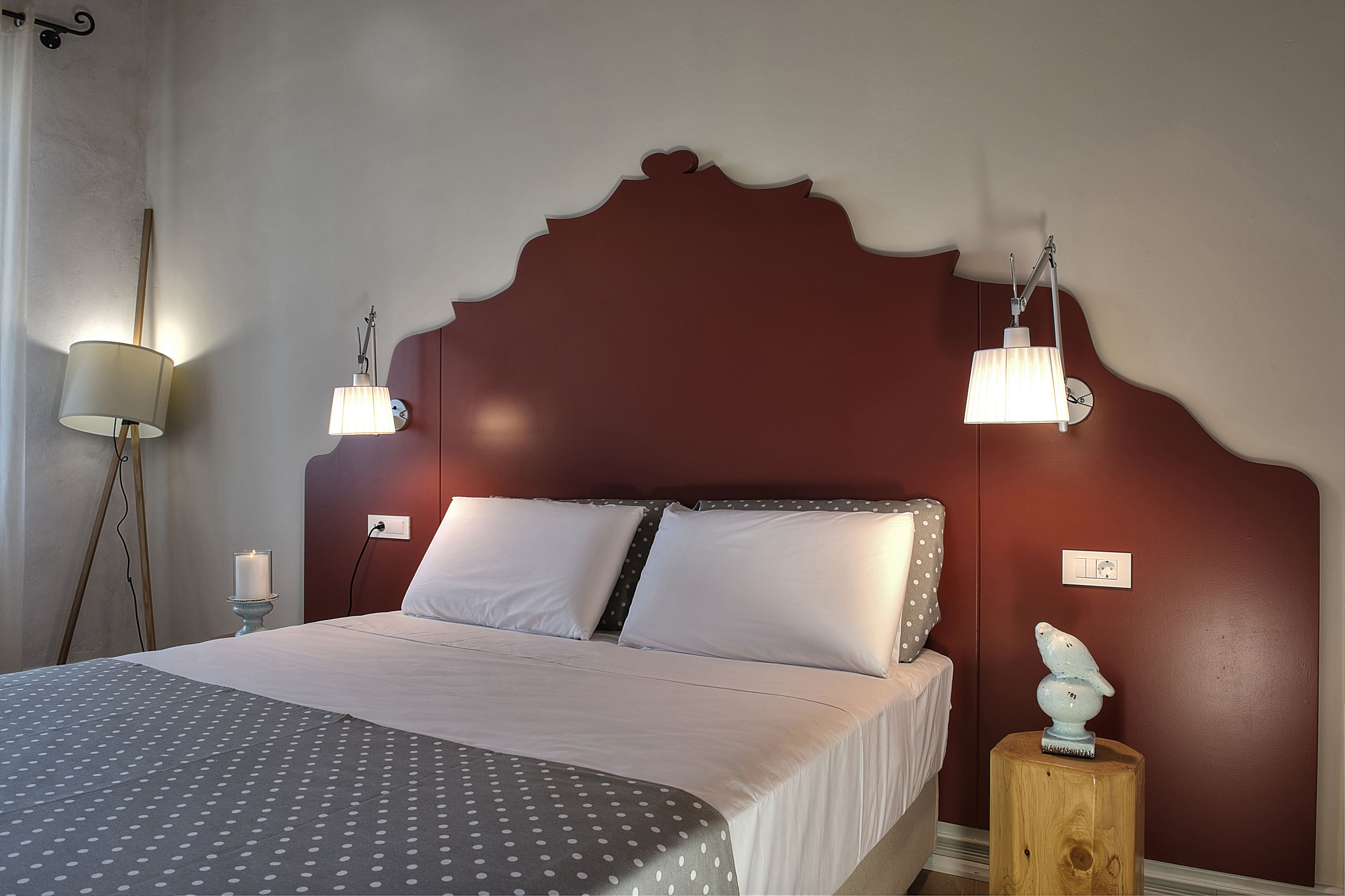 A neatly made bed with white and gray bedding, two bedside lamps, and a wooden nightstand with a decorative object.