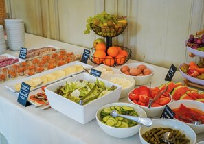 Un bufé con diversas opciones de comida, incluyendo ensaladas, frutas y quesos.