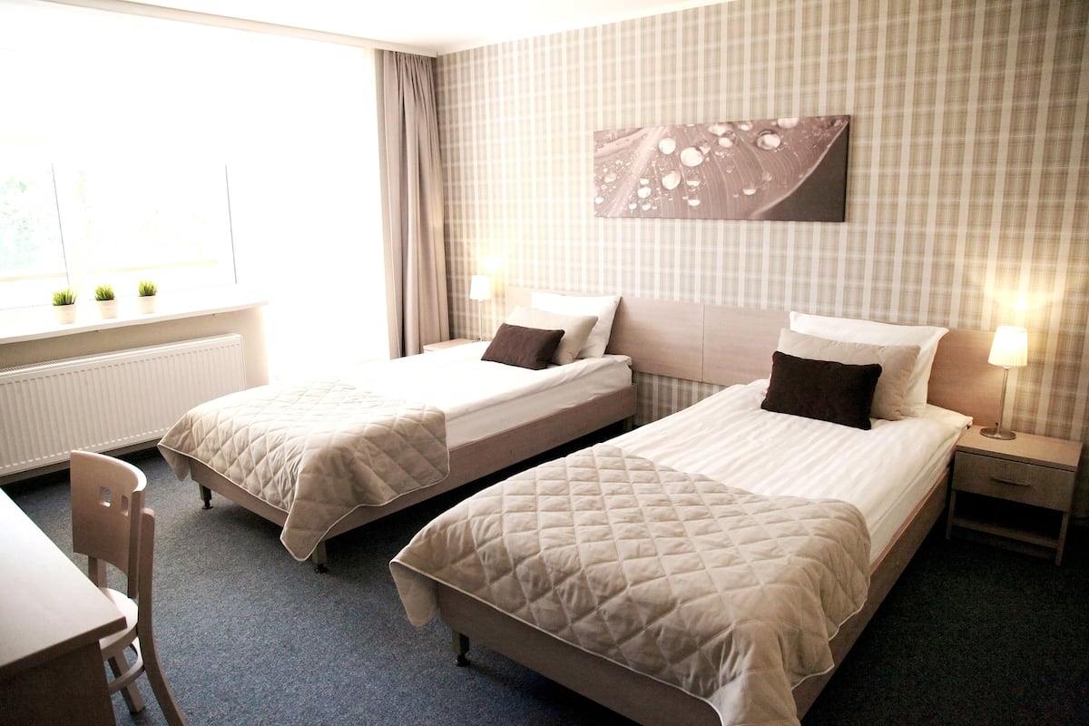 Habitación de hotel con dos camas, un escritorio y una silla.