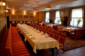 Una larga mesa de comedor con manteles blancos y bancos a rayas rojas, dispuesta para una comida formal.