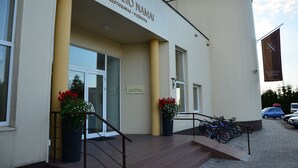 Een gebouw met een bord waarop staat: NYKŚCIO NAMAI RESTORANAS VIEŚBUJTS.