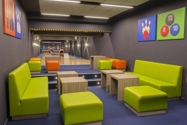 Un bowling avec des sièges verts et des pistes de bowling.