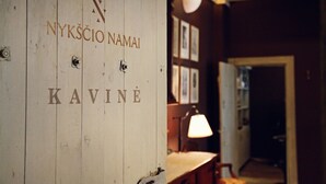 Una puerta de madera con el texto "NYKSĆO NAMAI" y "KAVINE".