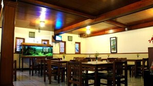 Un restaurante con mobiliario de madera, un acuario y cuadros en la pared.
