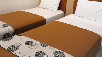 Une chambre d’hôtel avec deux lits simples, chacun recouvert d’une couverture marron et agrémenté d’un oreiller blanc. Un tableau est accroché au mur, au-dessus des lits.