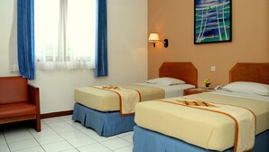 Habitación de hotel con dos camas, un sofá, una lámpara y un cuadro en la pared.