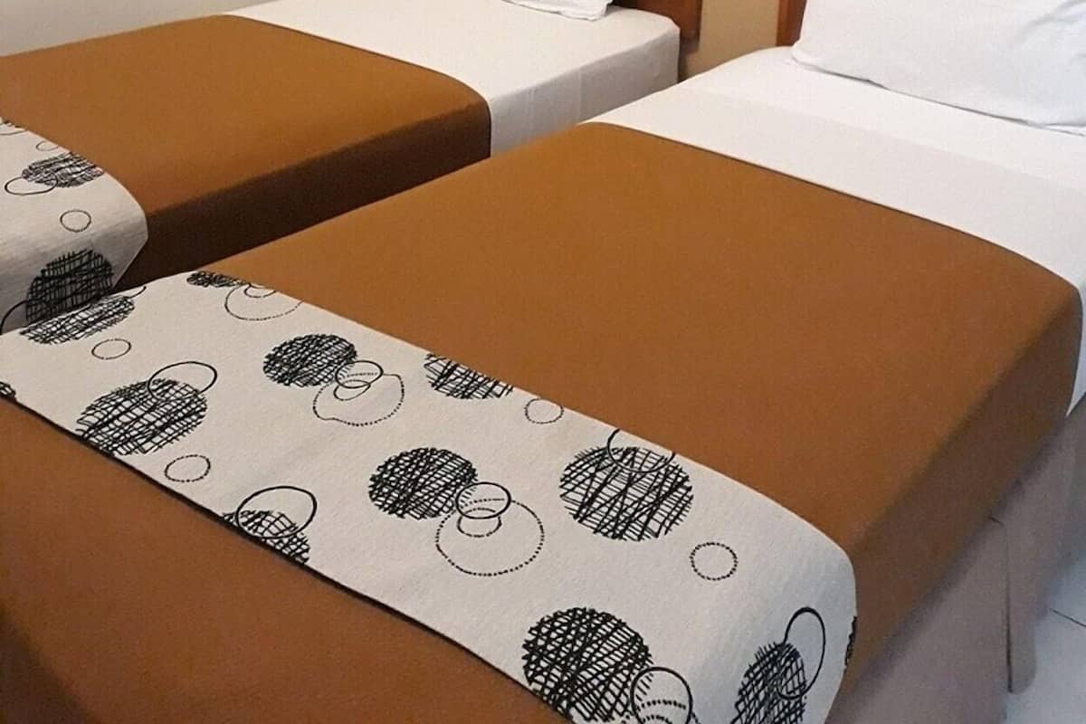 A hotel room with two single beds, a painting on the wall, and a white shelf.