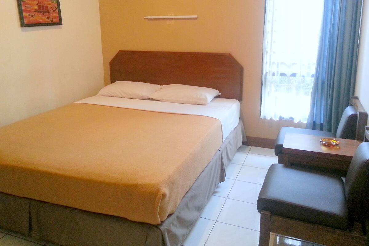 A hotel room with a bed, a desk, and a chair.