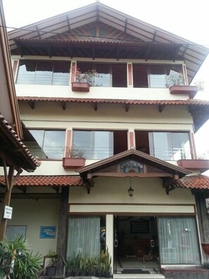 A multi-story building with a tiled roof, balconies, and a front entrance with glass doors. - Kenangan Hotel (Bandung)