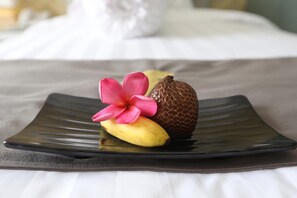 Un plato con un plátano, una flor y una fruta cubierta de chocolate.