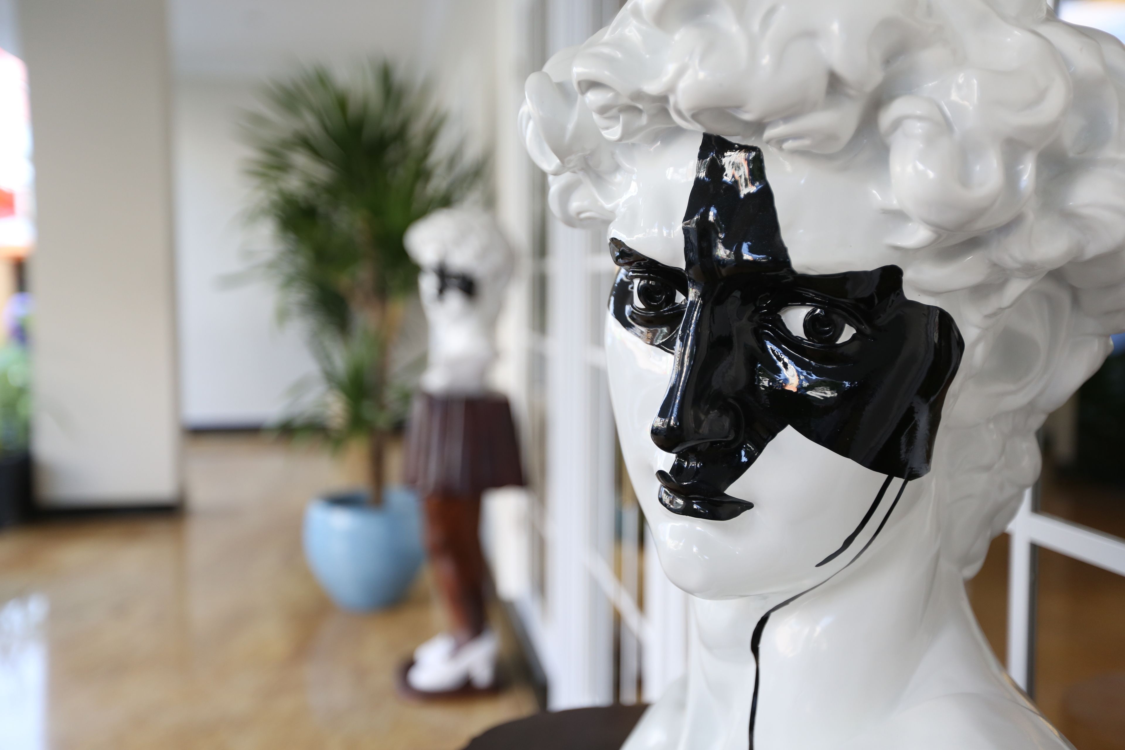 Una escultura de busto blanco con una máscara negra en un vestíbulo.