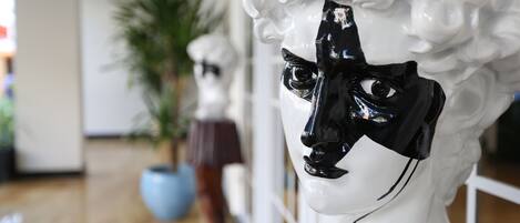 A white bust sculpture with a black mask in a lobby area.