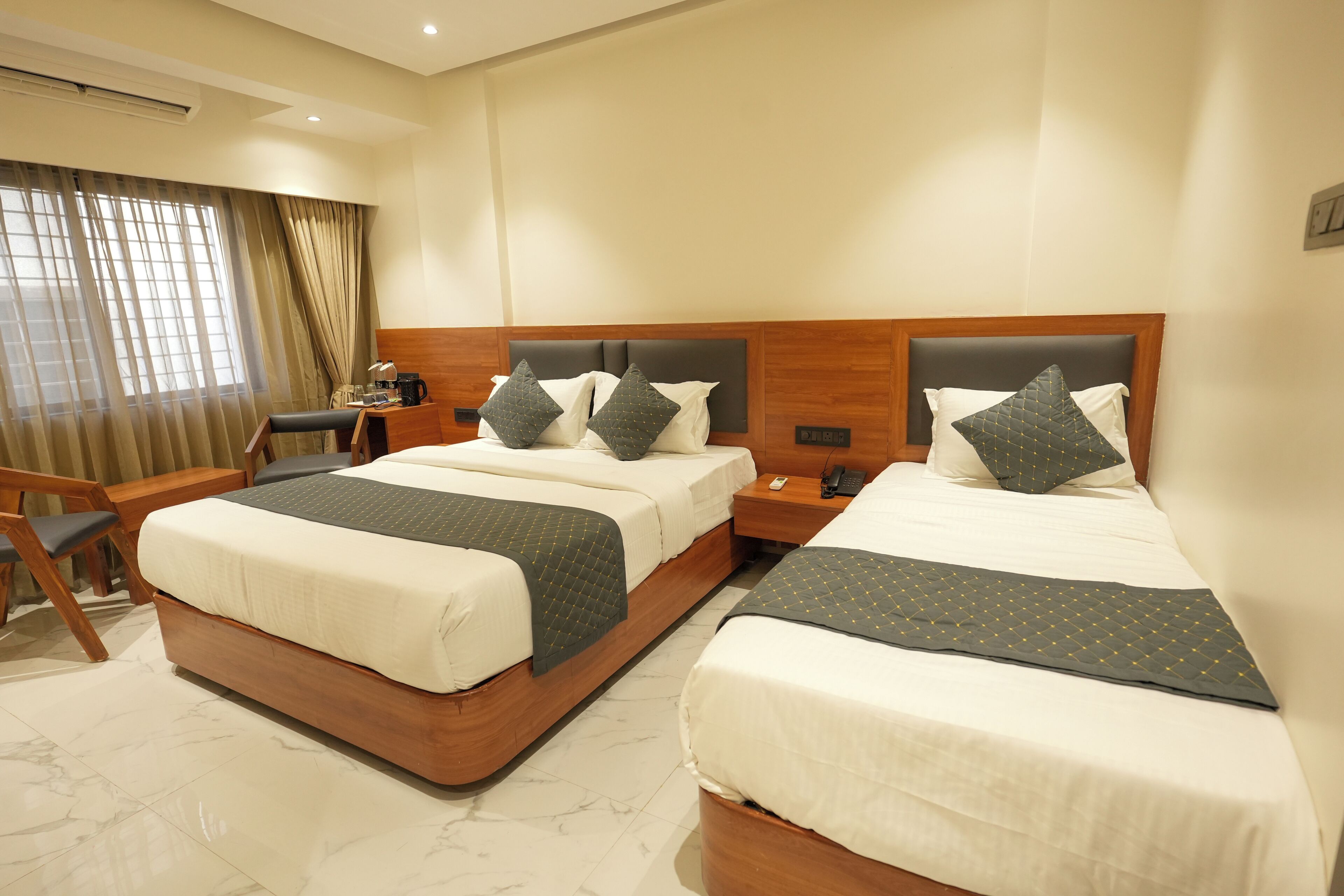 A hotel room with two beds, a desk, and a chair.