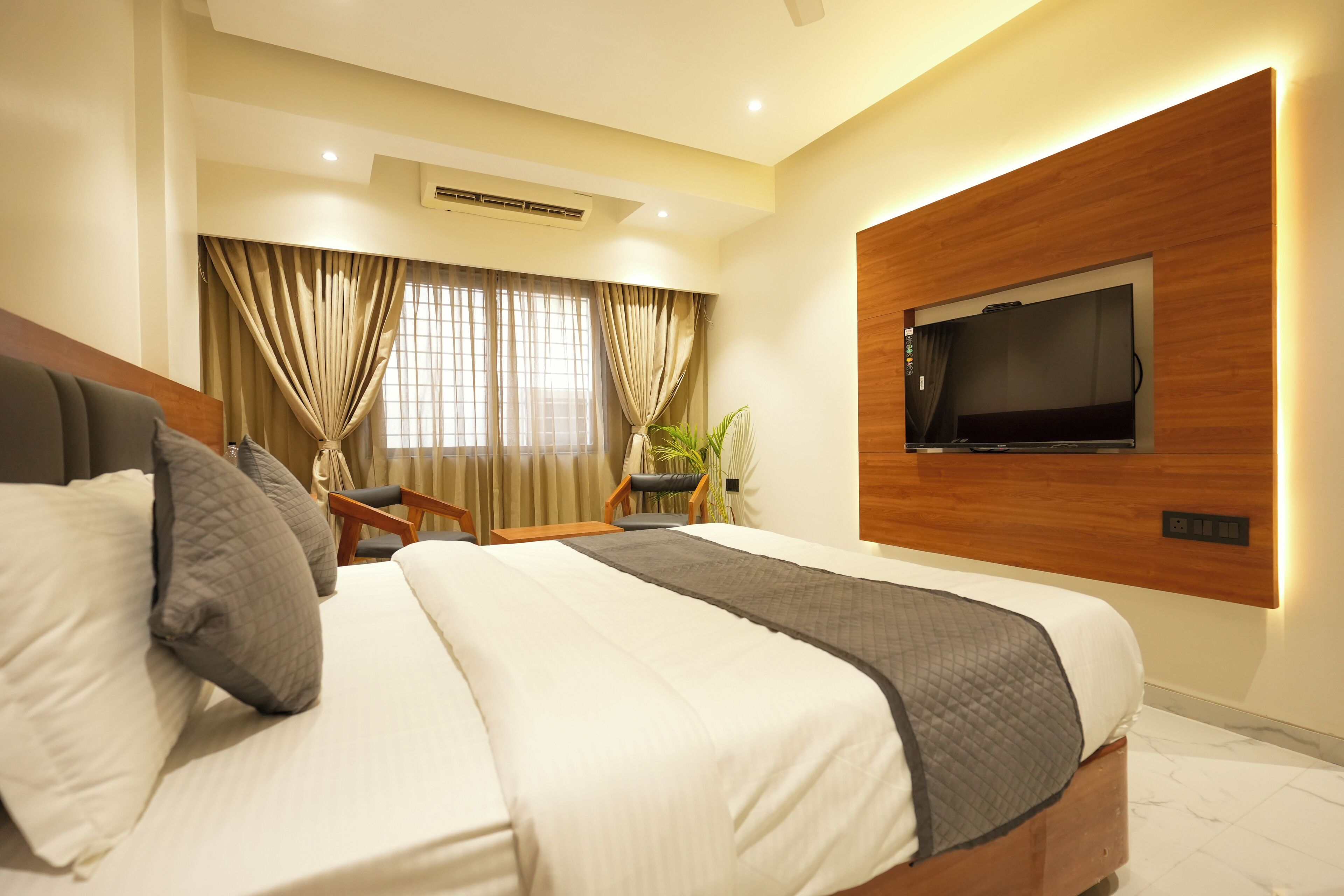 Una habitación de hotel moderna con una cama grande, un televisor en la pared y un escritorio con una silla.