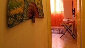 A hallway with a large wall-mounted fan, a table with items, and a door leading to another room. - Melone Giallo (Paceco)