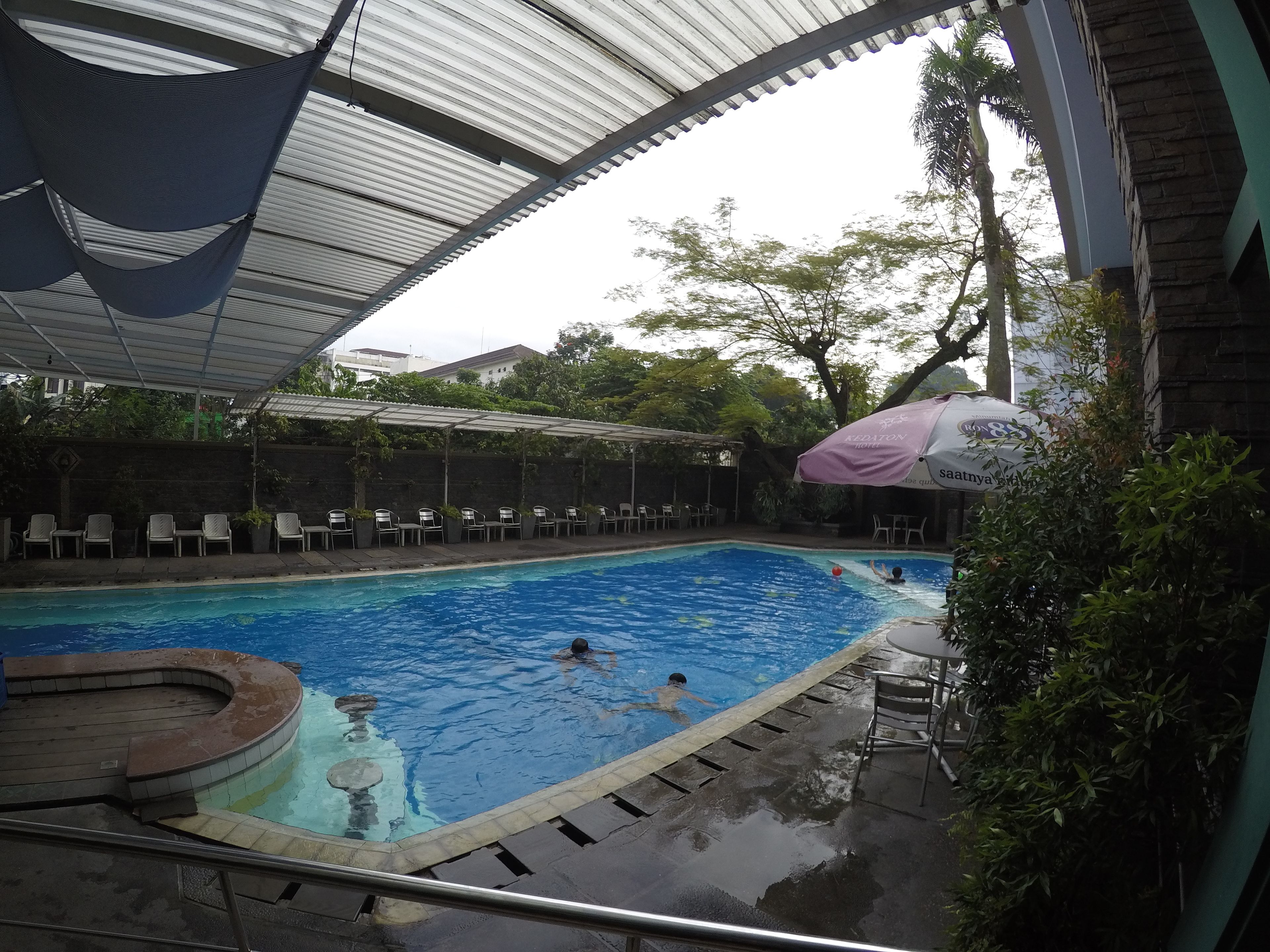 Una piscina con zona cubierta, sillas de descanso y una pequeña terraza.