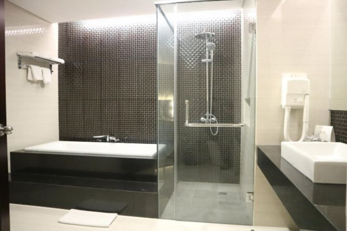 A modern bathroom with a glass-enclosed shower, a separate bathtub, and a vanity with a sink.