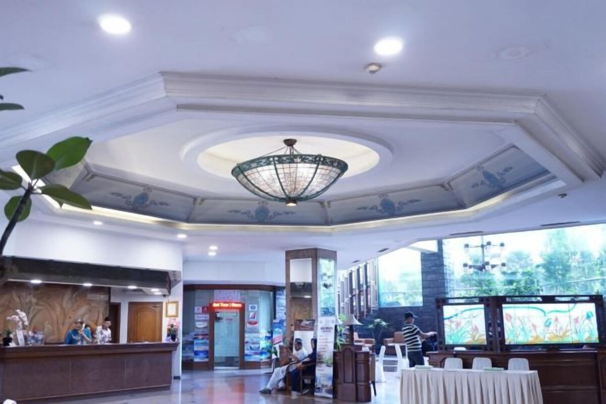 A hotel lobby with a reception desk, seating area, and large windows.