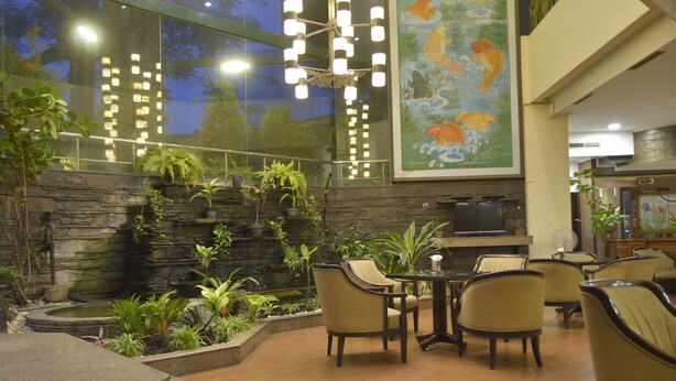 A restaurant with a stone wall, indoor plants, and a large fish mural. - Kedaton Hotel (Bandung)