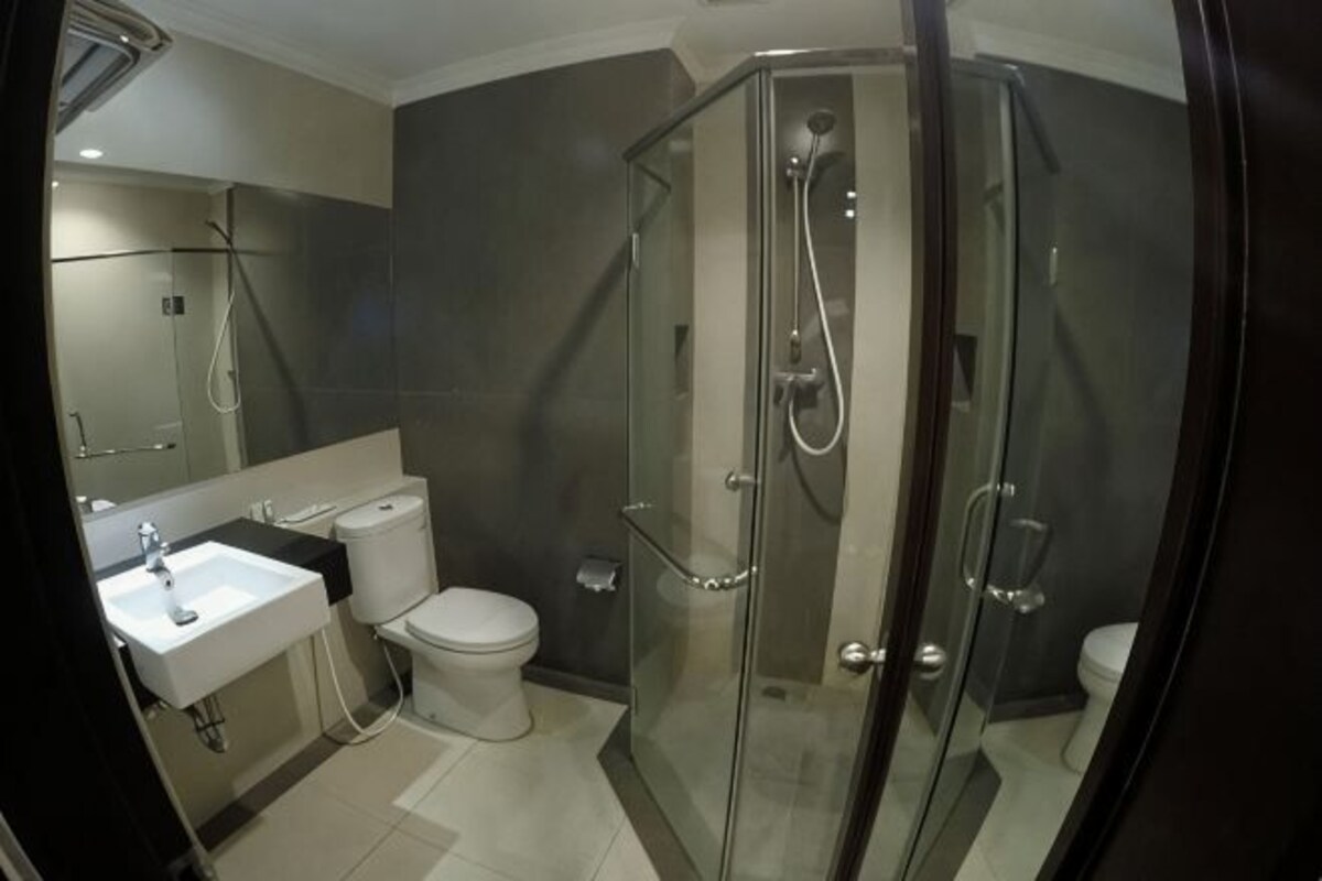 A modern bathroom with a glass-enclosed shower, a toilet, and a sink.