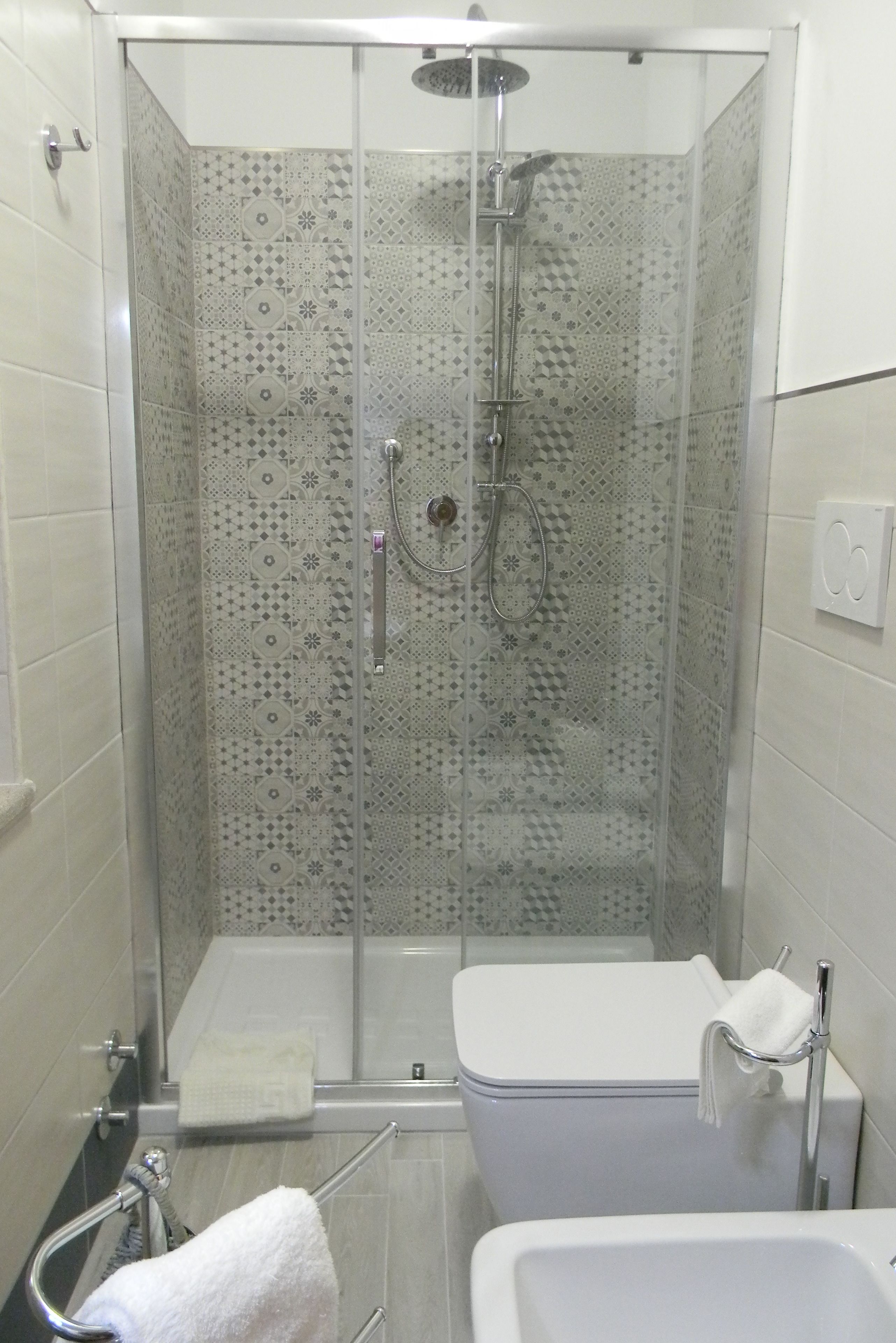 A modern shower with a glass door, a white toilet, and a sink with a towel rack.