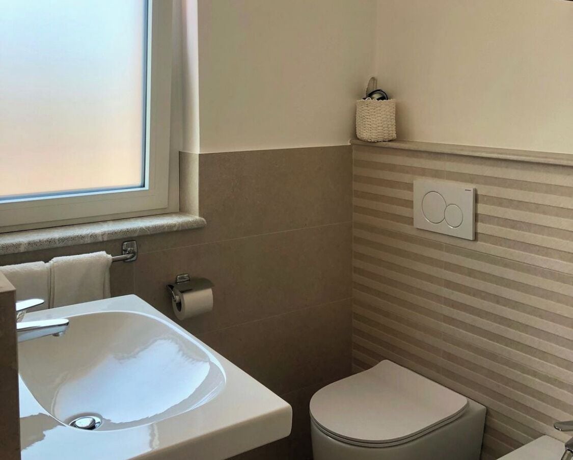 Un baño con lavamanos, inodoro y ventana.