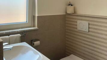 Un baño con lavamanos, inodoro y ventana.