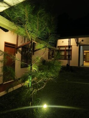 A building with a wooden door and windows, surrounded by greenery. - Elenor's Home at Eyckman (Bandung)