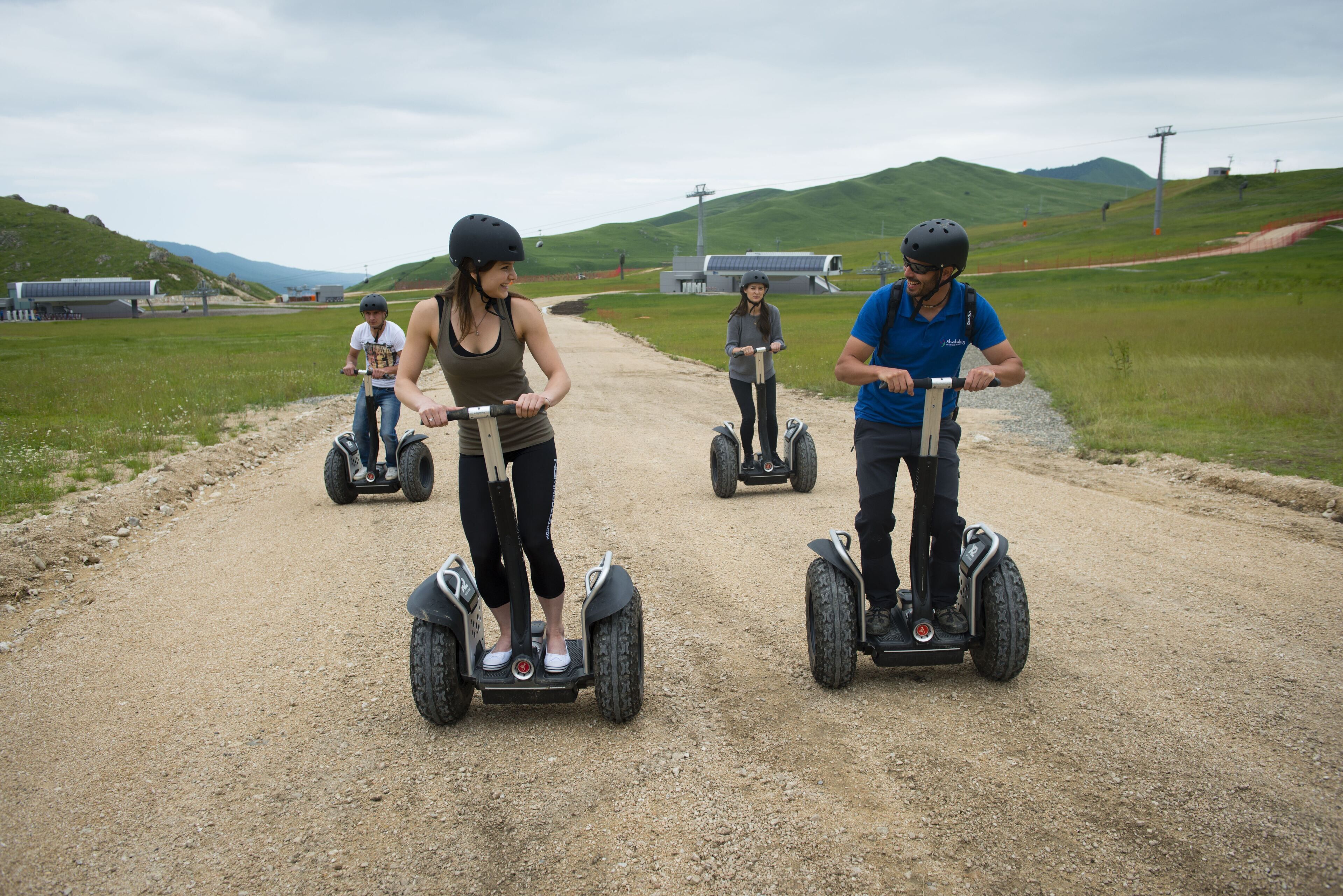 A group of people on segways on a gravel path with green hills in the background.
