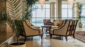 A lobby with a large potted plant, two armchairs, a coffee table, and a view through large windows. - Shahdag Hotel & Spa (Qusar)