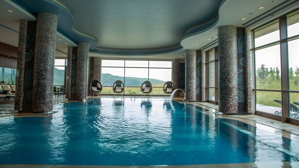 An indoor swimming pool with clear views of the outdoors, surrounded by large pillars and large windows. - Shahdag Hotel & Spa (Qusar)
