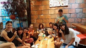 Un grupo de personas sentadas alrededor de una mesa de madera en una habitación con paredes de ladrillo y un mural.