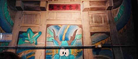 A room with a wooden ceiling and a large dragon mural.