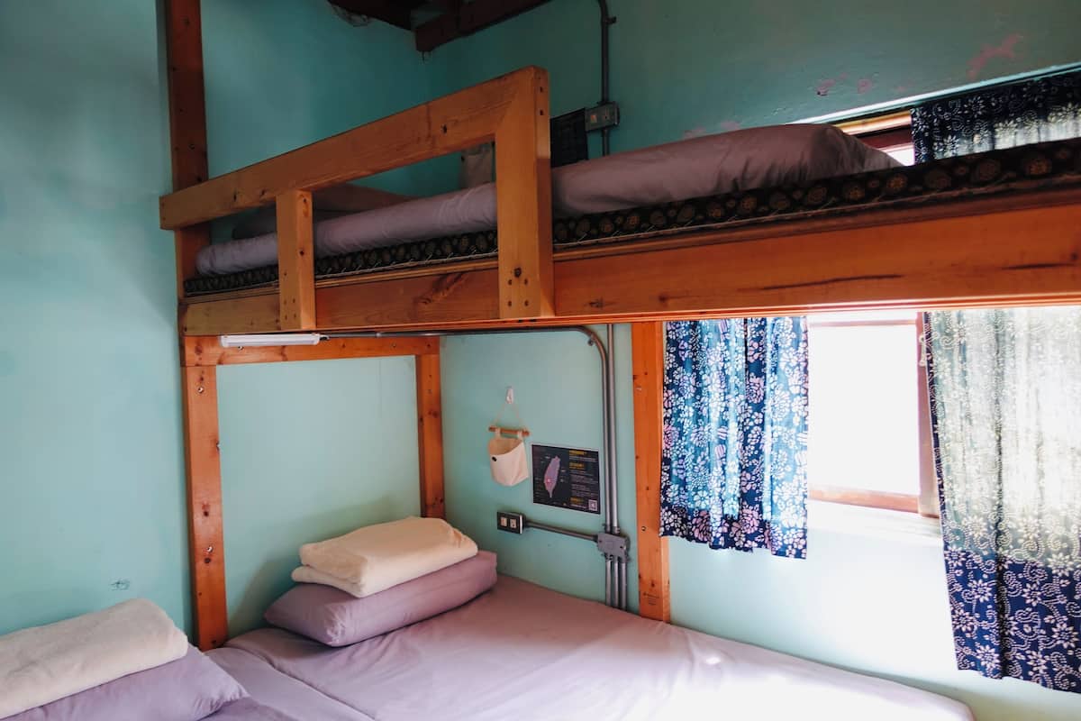 A bunk bed room with a window, a hanging bag, and a wall-mounted sign.