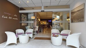 Un hall de hotel con mobiliario de mimbre, una pared con un mensaje y vistas al interior.