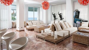 A spacious living room with a large sofa set, wicker coffee tables, and a piano. - Hotel Croce di Malta (Jesolo)