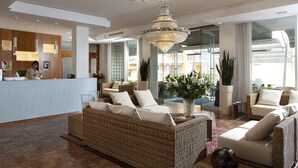 A spacious lobby with a reception desk, wicker sofas, a large chandelier, and a view of the outside. - Hotel Croce di Malta (Jesolo)